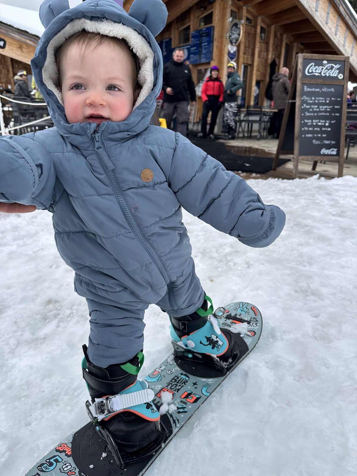 A little one's first snowboard by the mountain restaurant